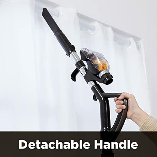 Person using a vacuum cleaner with a detachable handle.